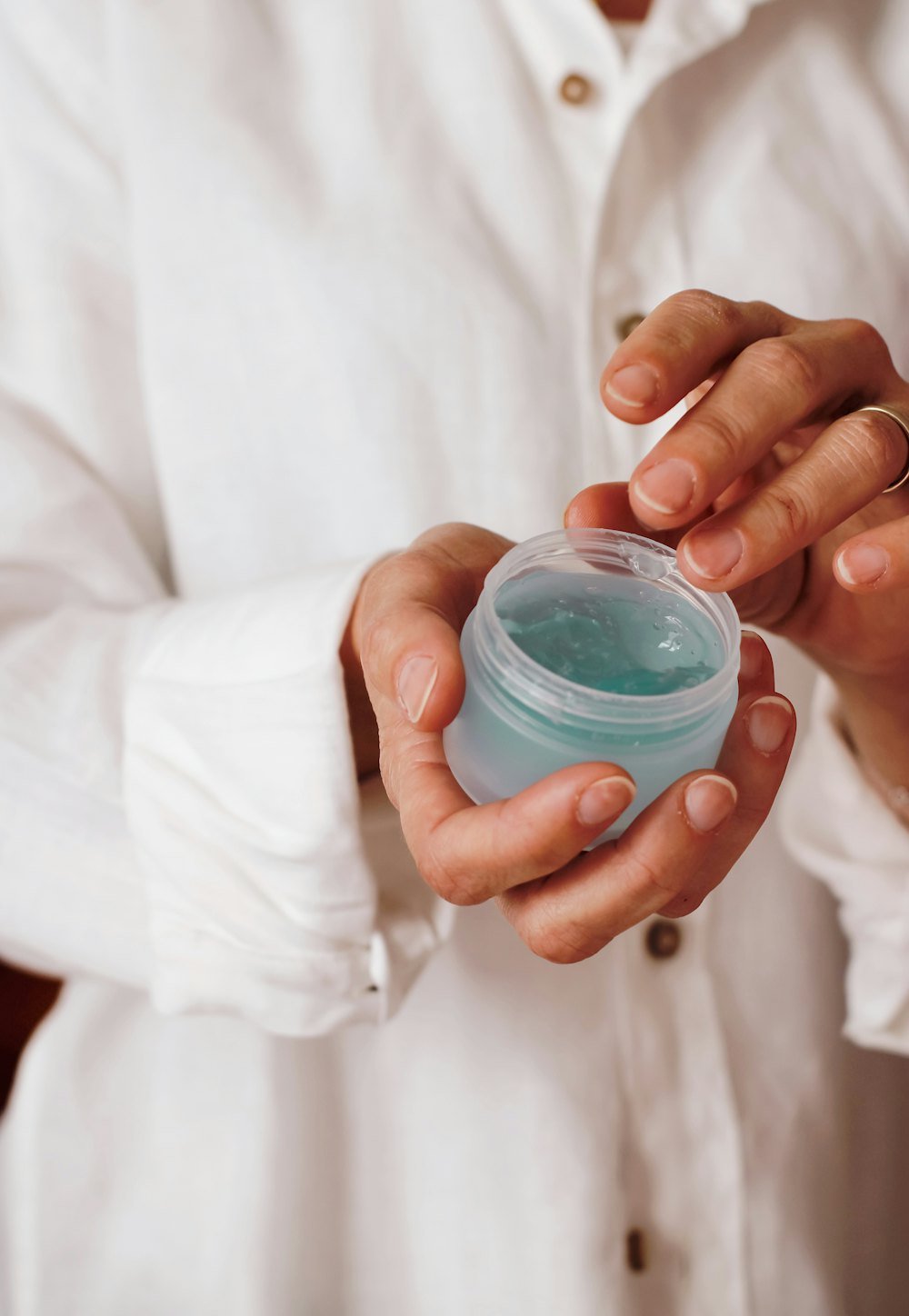 Hands holding an open jar of skincare cream