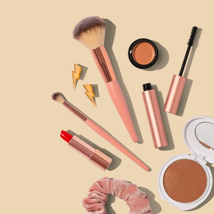 Makeup brushes and cosmetics on a beige surface