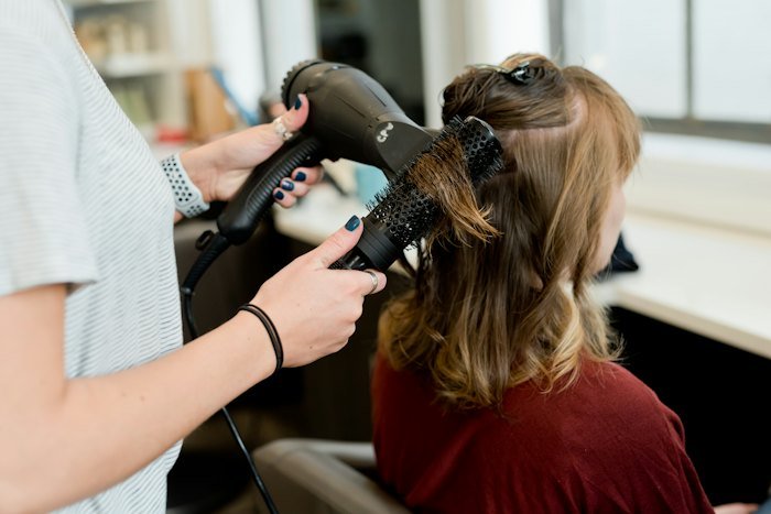 Stylist blow-drying a client's hair with a professional dryer