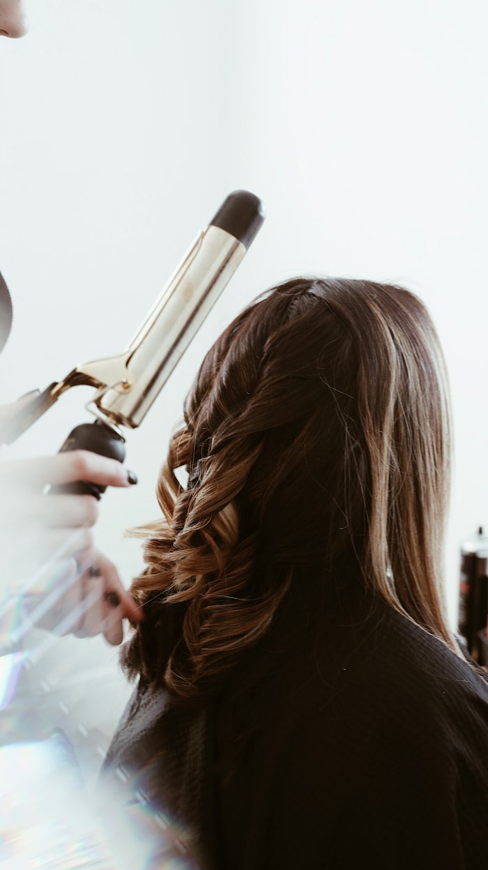 Stylist curling long hair with a heated styling tool