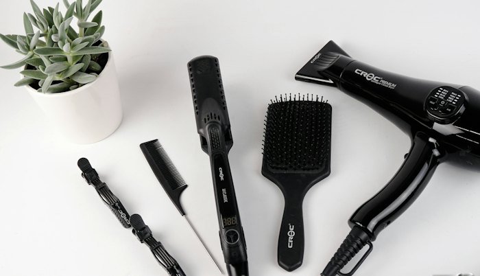 Hair straightener, brushes and styling tools on white